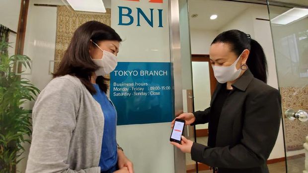 Pegawai sedang menjelaskan fitur-fitur yang terdapat pada aplikasi BNI Mobile Banking di Kantor Cabang Luar Negeri BNI Tokyo. BNI membuka kesempatan bagi karyawannya untuk magang di salah satu kantor cabang luar negerinya, yaitu Singapura, Tokyo, Hong Kong, London, New York, atau Seoul.